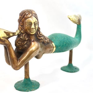 May include: A brass mermaid door knocker with a green tail and a seashell in her hand.