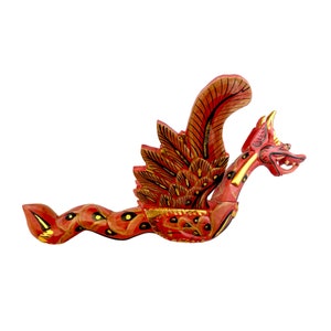 May include: A red and gold wooden dragon with wings outstretched, carved and painted in a traditional style. The dragon has a long, serpentine body and a fierce expression.