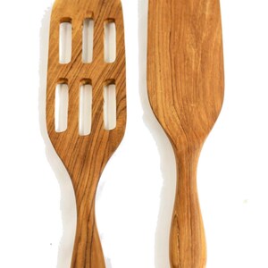 May include: Two wooden kitchen spatulas, one with a slotted design and the other solid. Both have a natural wood finish and a rounded handle.