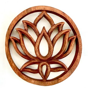 May include: A circular wooden wall decoration featuring a carved lotus flower design. The flower is intricately detailed and has a natural wood finish.
