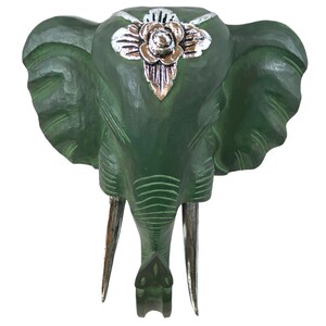 May include: Green wooden elephant head wall decor with silver floral accents. The elephant has long tusks and a detailed carved face.
