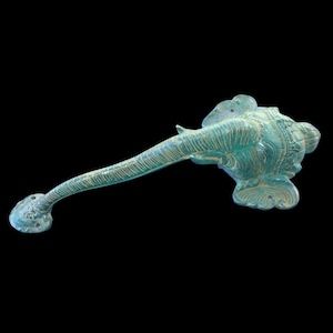 May include: A teal blue metal door handle shaped like an elephant head with intricate details. The handle is designed to be used as a pull handle.