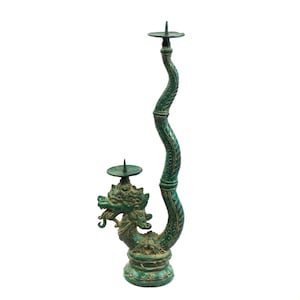 Könnte beinhalten: Ein grüner Kerzenhalter aus Metall in Form eines Drachen mit zwei Kerzenbechern. Der Drache ist zusammengerollt, wobei sein Schwanz die Basis des Halters bildet.