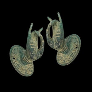 May include: Two antique bronze wall hooks shaped like hands making a gesture of blessing. The hands are intricately carved and mounted on circular bases with decorative designs.