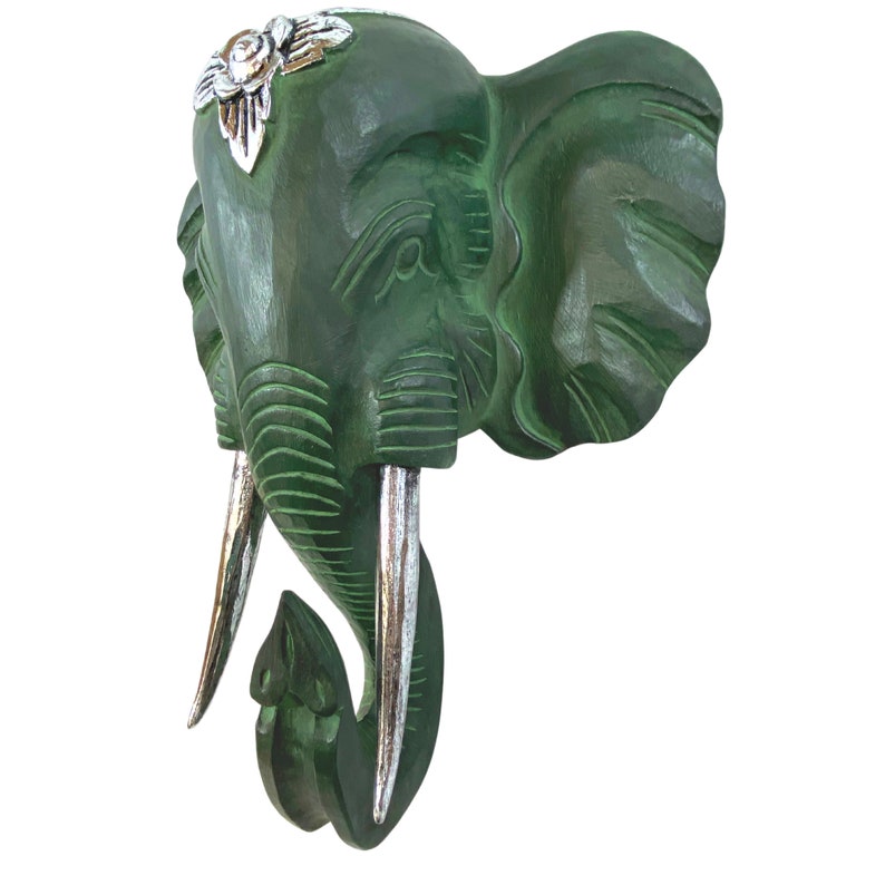 May include: Green wooden elephant head wall decor with silver tusks and floral accents.