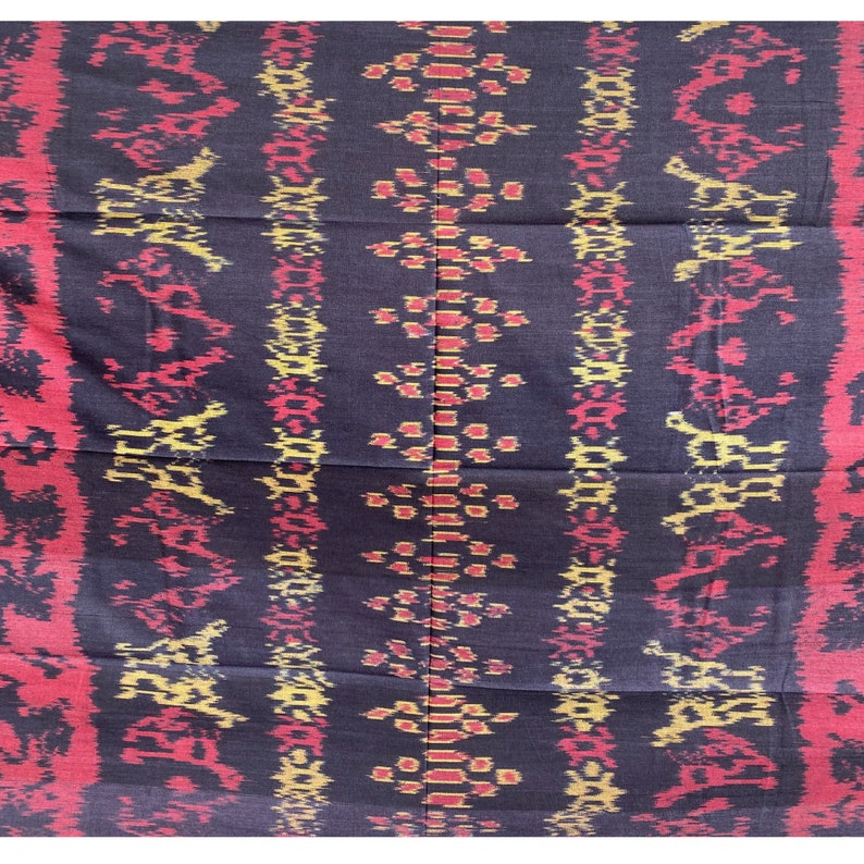 May include: Black fabric with a repeating pattern of red, yellow, and white geometric shapes. The fabric has a woven texture.