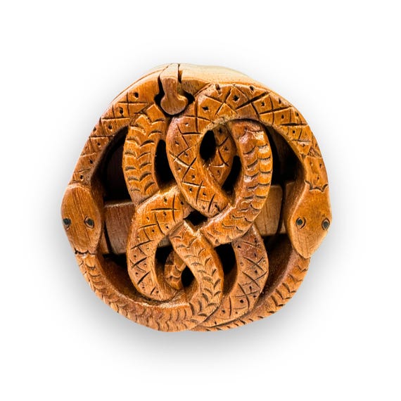 A hand-carved Celtic knot snake puzzle box that doubles as a secret stash — you have to solve it to get inside.