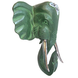 May include: Green wooden elephant head wall decor with silver tusks and floral accents.