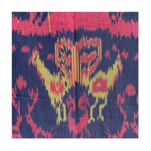 May include: A close-up of a dark blue fabric with a repeating pattern of red, yellow, and gold. The pattern is abstract and resembles a stylized bird.