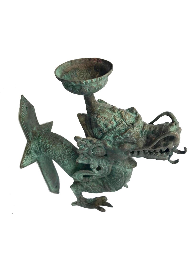 May include: An antique bronze dragon-shaped incense burner. The dragon has a detailed head with open jaws and a small bowl held above its head. The dragon's body is intricately detailed with scales and decorative elements.
