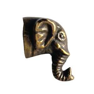 Puede incluir: Una pequeña figurita de elefante de metal de color dorado con una trompa y una oreja detalladas. La figurita es de diseño tradicional y sería una excelente adición a cualquier decoración del hogar.