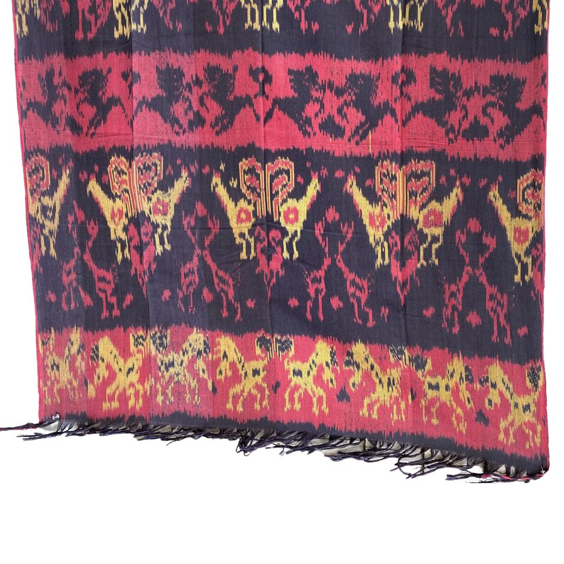 May include: A black, red, and gold woven textile with a repeating pattern of stylized animals. The textile has a fringed edge.