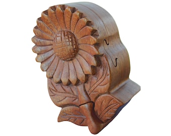 May include: A wooden puzzle box shaped like a sunflower with intricate carvings. The box is made of dark brown wood and has a hinged lid that opens to reveal a secret compartment.