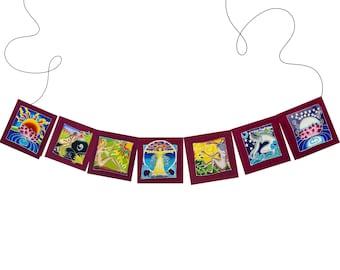 Op de afbeelding: Een bordeauxrode stoffen banner met zeven kleurrijke vierkanten met verschillende afbeeldingen van vrouwen, bloemen en hemellichamen. De banner is aan een zwart koord geregen.
