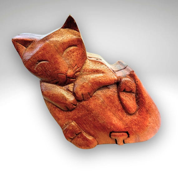 A hand-carved wooden puzzle box shaped like a cat — you have to solve it to get inside, making it a gift that's also a tiny game.