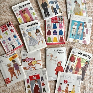 May include: A collection of vintage sewing patterns for children's clothing. The patterns feature illustrations of dresses, overalls, and other outfits. Brands include Simplicity, McCall's, and Butterick. The patterns are in various sizes and styles.