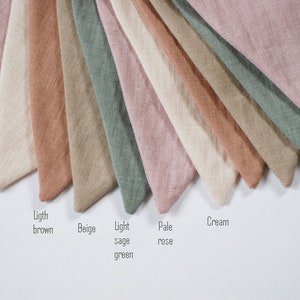 Puede incluir: Una colecci&oacute;n de muestras de tela en varios tonos de beige, marr&oacute;n, rosa, verde y crema. Las muestras est&aacute;n dispuestas en forma de abanico con los nombres de cada color escritos debajo.