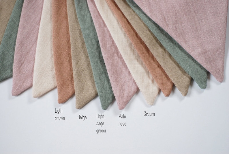Puede incluir: Una colecci&oacute;n de muestras de tela en varios tonos de beige, marr&oacute;n, rosa, verde y crema. Las muestras est&aacute;n dispuestas en forma de abanico con los nombres de cada color escritos debajo.