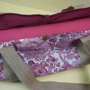 May include: A floral print yoga mat bag with a matching yoga mat inside. The bag features a white background with a burgundy floral pattern, burgundy lining, and tan handles. A wooden button secures the bag.