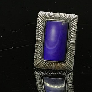 May include: A silver ring with a rectangular purple stone set in a textured frame.