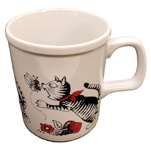 May include: White ceramic mug with a black and white cat illustration chasing a bee. The cat has a red bow tie and is near a red flower and a small overturned pot. The mug has a curved handle.