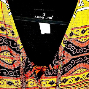 May include: A Carole Little top featuring a vibrant yellow, orange, and black patterned design with a V-neckline and a black interior lining. The fabric displays a repeating geometric and paisley-inspired motif throughout the garment.
