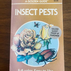 May include: A Golden Guide book titled Insect Pests with a tan cover featuring a circular illustration of yellow roses and various beetles. The text reads A Golden Guide, Insect Pests, Full-color, Easy-to-Use, and Golden Guide Proof of Purchase.