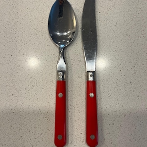 May include: A set of two silver utensils with red plastic handles. The utensils include a spoon and a butter knife.