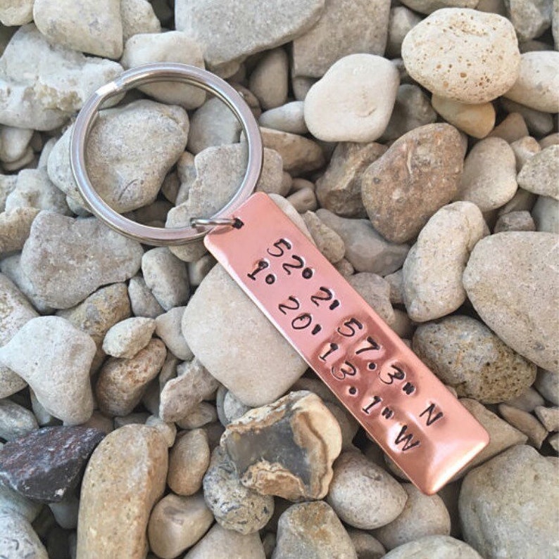 May include: A copper keyring with a silver key ring. The keyring has the coordinates 52.21.57.3&deg; N 1.20.11.3&deg; W engraved on it.