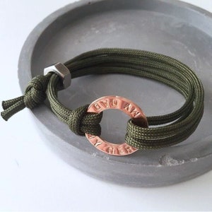 May include: A green paracord bracelet with a copper-colored metal ring that says "God  Now  My  Her".