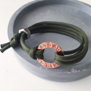 May include: A green paracord bracelet with a copper ring charm that says "My Dad" around the outside.