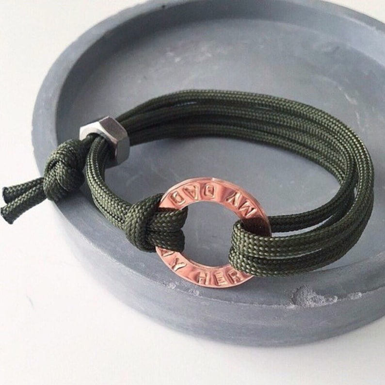 May include: A green paracord bracelet with a copper ring charm that says "My Dad" around the outside.