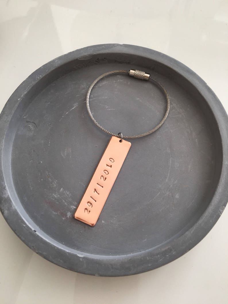May include: A copper keychain with a silver cable chain and a rectangular tag engraved with the date "2017112010".