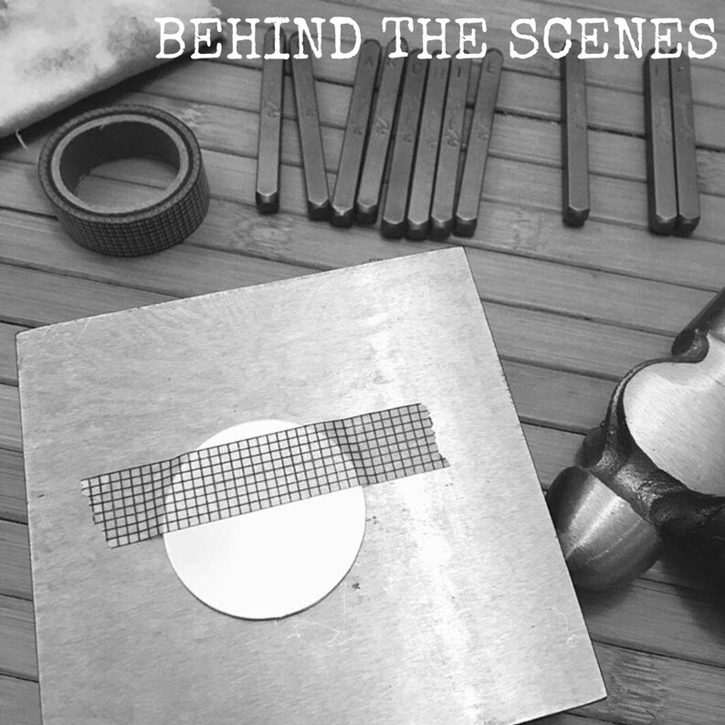Op de afbeelding: Een close-up van een metalen oppervlak met een ronde, witte schijf bedekt met een rasterband. Een hamer en een set metalen letterstempels zijn ook zichtbaar op de afbeelding. De tekst "BEHIND THE SCENES" is bovenaan de afbeelding gedrukt.