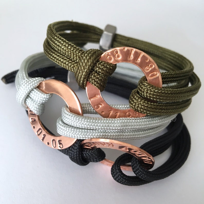 May include: Three braided bracelets with copper rings. The rings have engraved numbers, "68.11.80", "13.11.93", and "04.01.05".