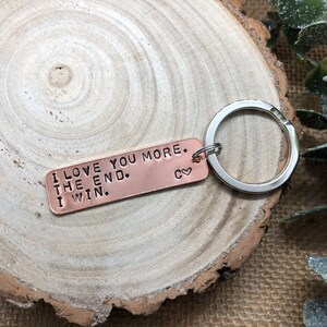 May include: Copper keychain with the text "I love you more. The end. I win." and a small heart with the letter "C" on it.