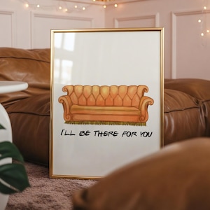 May include: A rectangular wall art print in a thin gold frame featuring a centered illustration of an orange tufted sofa. Below the sofa, the black text reads I'LL BE THERE FOR YOU. The print is set against a white background, showcasing a clean design.