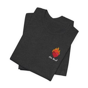 Peut inclure: Un t-shirt gris foncé chiné avec un graphique de cœur rouge en feu et le texte "Fire Heart" en blanc.