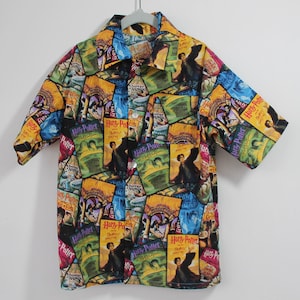 May include: A colorful button-down shirt with a Harry Potter theme. The shirt is made of a lightweight fabric and features a variety of Harry Potter book covers printed on it.