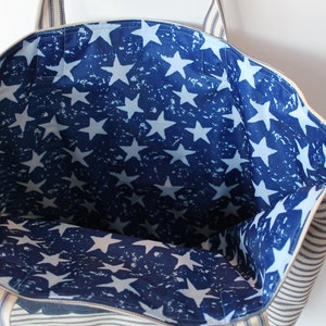 May include: A white and blue striped tote bag with a blue and white star print lining. The bag has two handles.