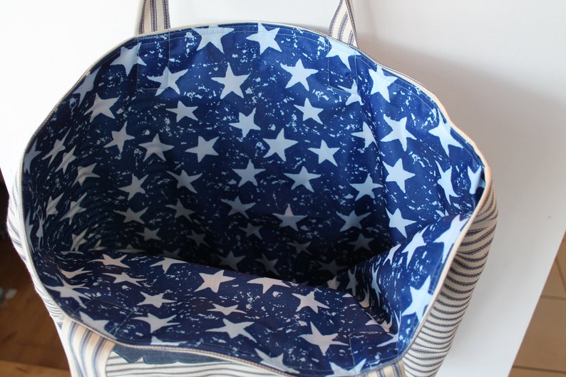 May include: A white and blue striped tote bag with a blue and white star print lining. The bag has two handles.
