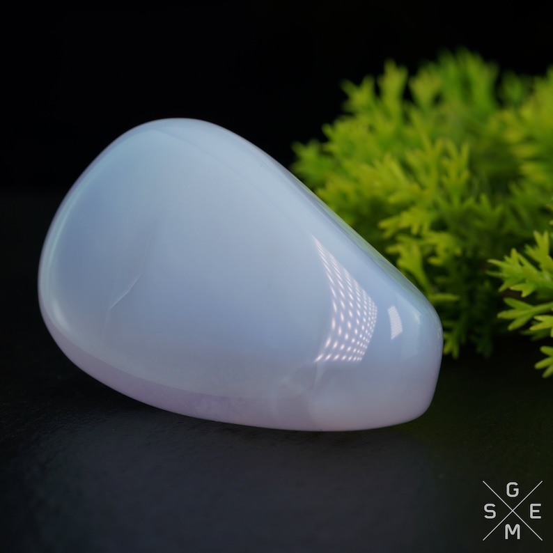 Pode incluir: Uma pedra de calced&ocirc;nia lisa, de cor azul p&aacute;lida, em forma de l&aacute;grima. A pedra &eacute; polida e tem uma apar&ecirc;ncia transl&uacute;cida.