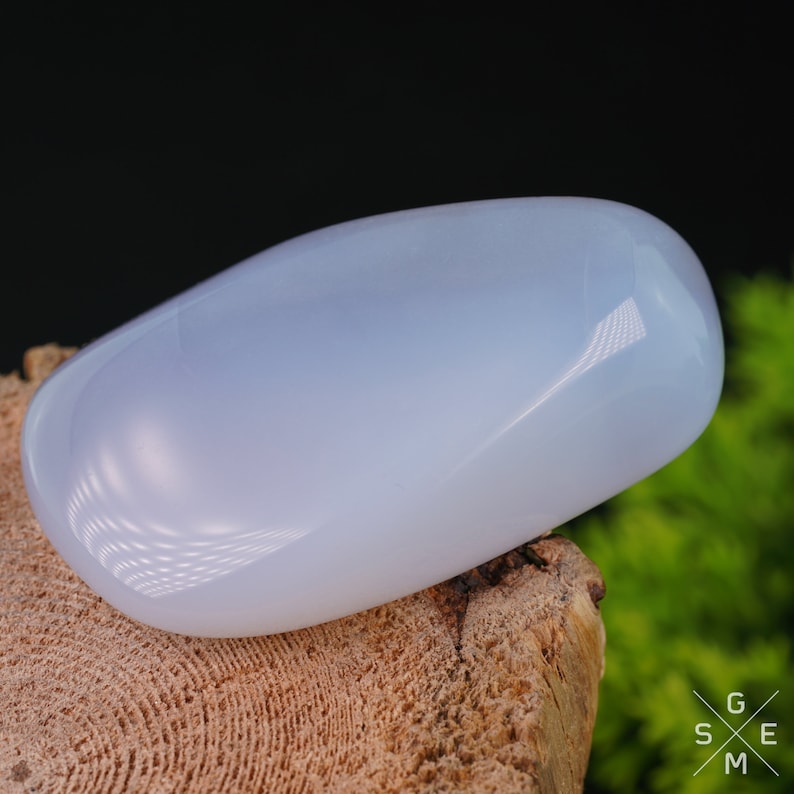 Pode incluir: Uma gema de calced&ocirc;nia lisa, azul claro, polida a alto brilho. A pedra tem formato oval e tem uma apar&ecirc;ncia transl&uacute;cida.