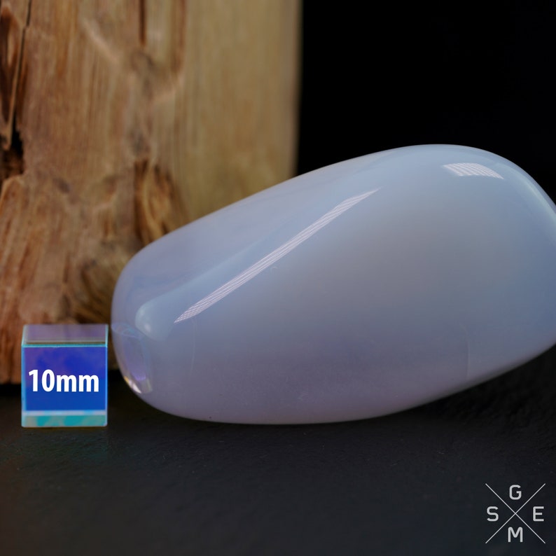 Pode incluir: Uma gema oval, lisa, azul claro e polida. A gema tem aproximadamente 10 mm de tamanho.