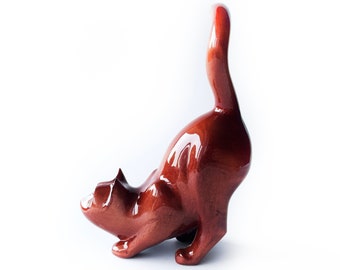 Figura de gato de madera roja oscura tallada a mano, en posición agachada.