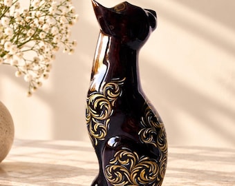 Figura de gato de madera tallada a mano con patrón pintado en oro y blanco.