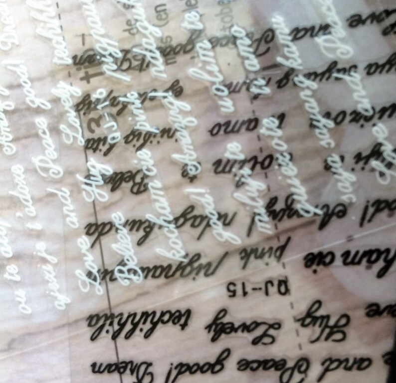 May include: A close-up of a clear sheet of paper with white lettering on top of a sheet of paper with black lettering. The white lettering says "Love and Peace good! Dream" and "Love Hug Lovely techinh" and "Love and Peace good! Dream". The black lettering says "Good! Amazing! ndagu" and "ham cie pink pigna" and "we and Peace" and "saya sayang kamu".