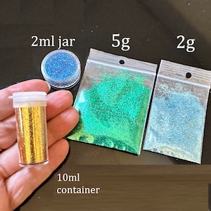 May include: Assortment of glitter in various colors and sizes.  A small 2 ml jar of blue glitter, a 5 g bag of green glitter, a 2 g bag of light blue glitter, and a 10 ml container of gold glitter.