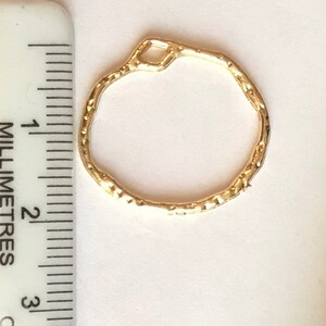 May include: Gold-toned metal ring with a textured surface. The ring is approximately 2 cm in diameter.