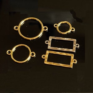Peut inclure: Cinq breloques de connecteurs en métal doré et argenté pour la fabrication de bijoux. Deux sont rondes, deux sont rectangulaires et une est un cercle texturé.